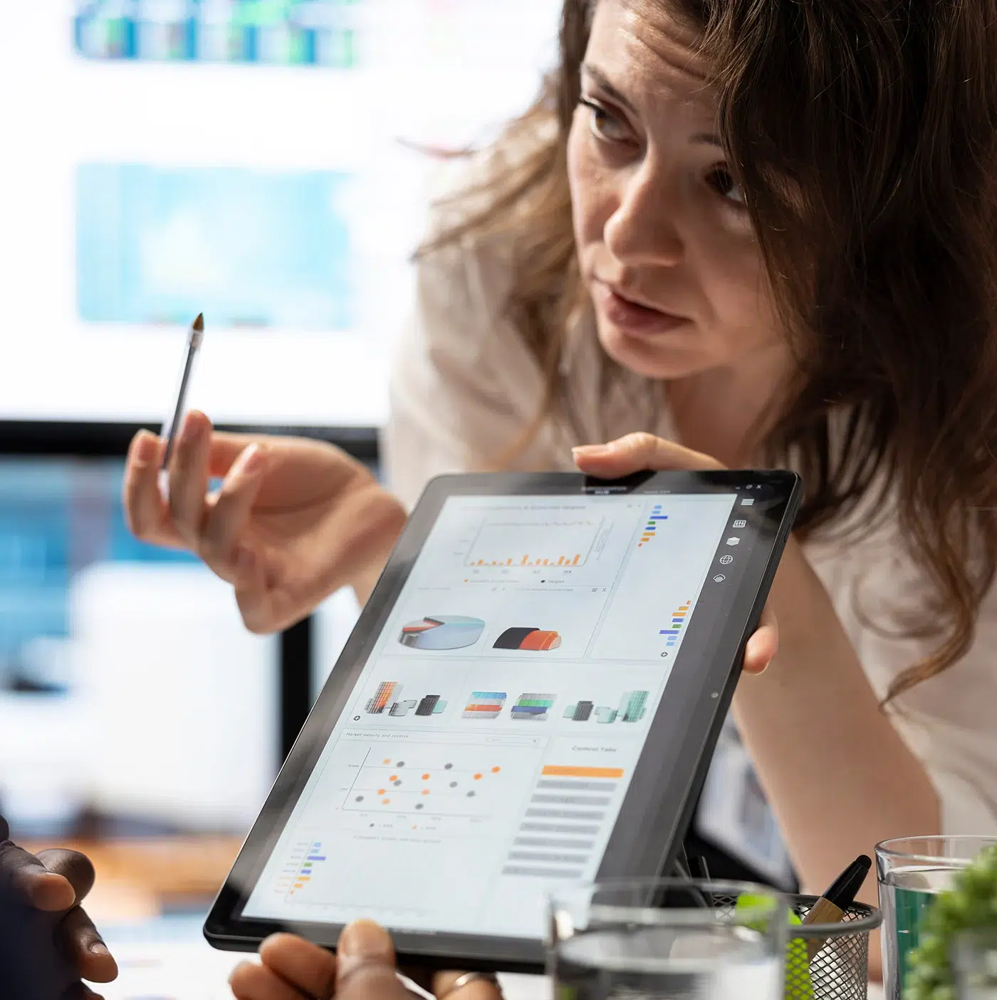 Woman explaining data visualizations on a tablet to a colleague in a meeting