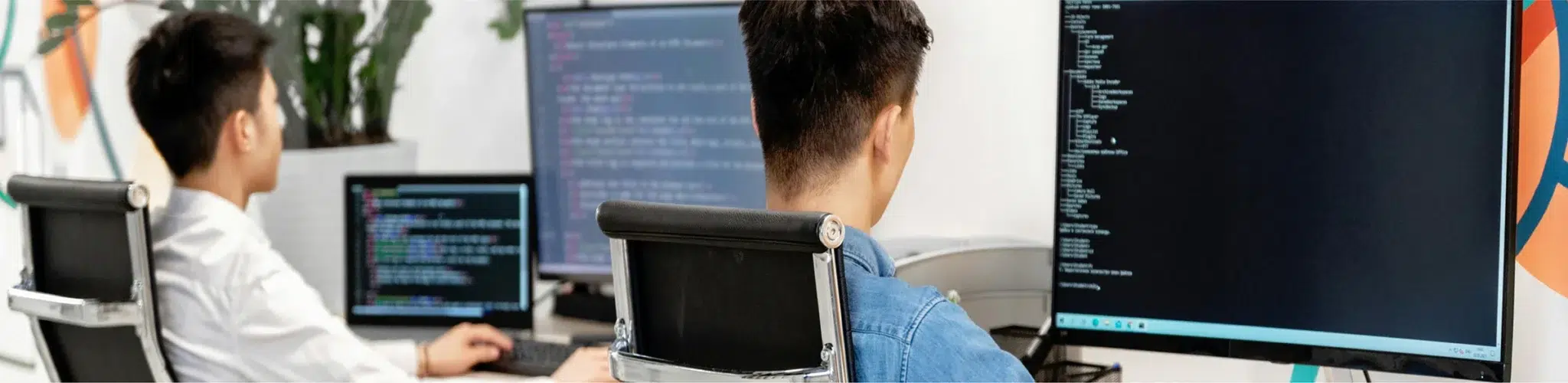 Person participating in a video conference with colleagues displayed on the screen while using a laptop in a modern workspace